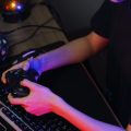 Female cyber hacker gamer playing or streaming video games on computer with joystick in neon light