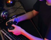 Female cyber hacker gamer playing or streaming video games on computer with joystick in neon light