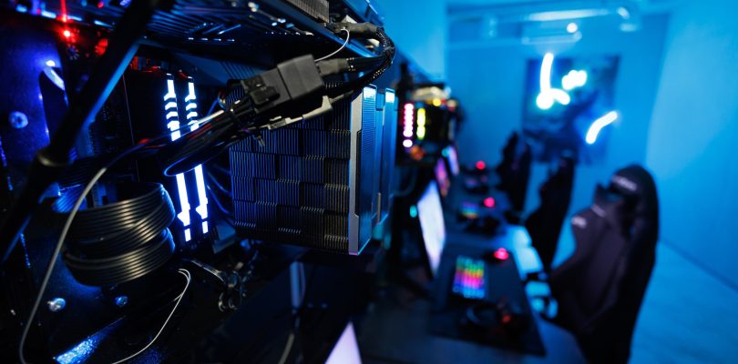 Computer club, monitors, keyboards and headphones in neon lighting, esports equipment.