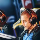 Team of four professional cybersport gamers wearing headphones participating in eSport tournament