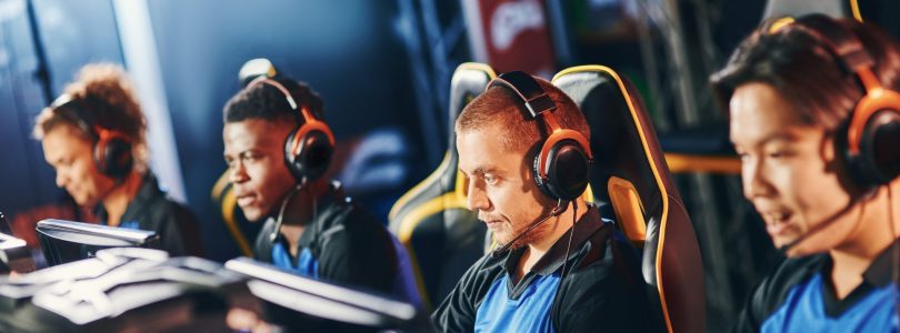 Team of four professional cybersport gamers wearing headphones participating in eSport tournament