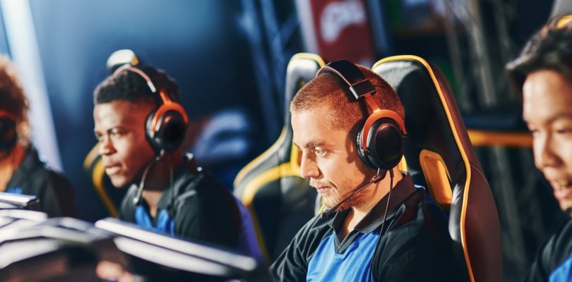 Team of four professional cybersport gamers wearing headphones participating in eSport tournament